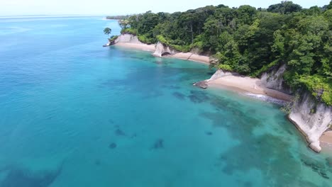 Forward-Flying-Aerial-of-Jungle-Island-with-Tropical-Trees,-Unigue-Cliffs-and-White-Beaches