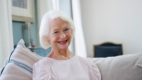 portrait of smiling senior woman sitting on sofa at home