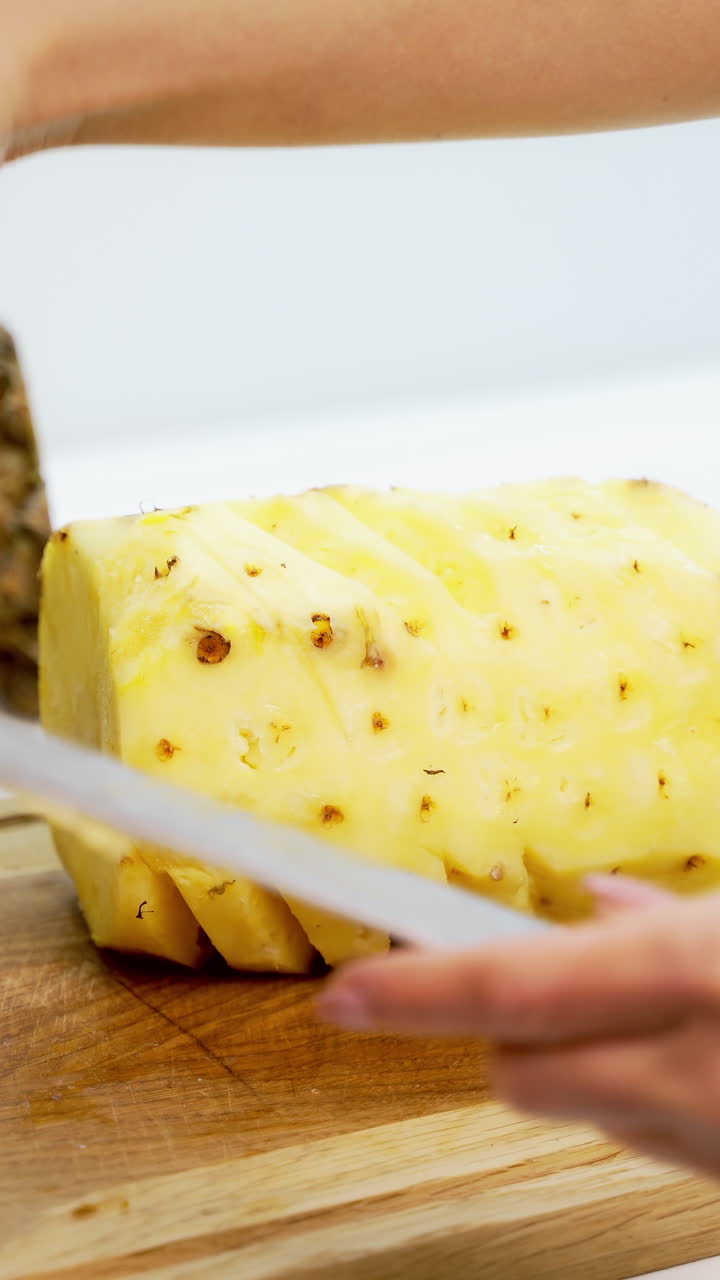 Hands slicing pineapple. Person slicing ripe pineapple with knife on table