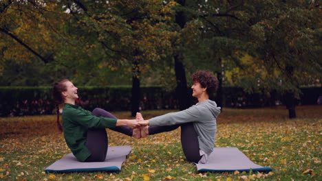 two women practicing partner yoga in an autumn park