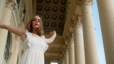 woman dancing in a white dress by columns