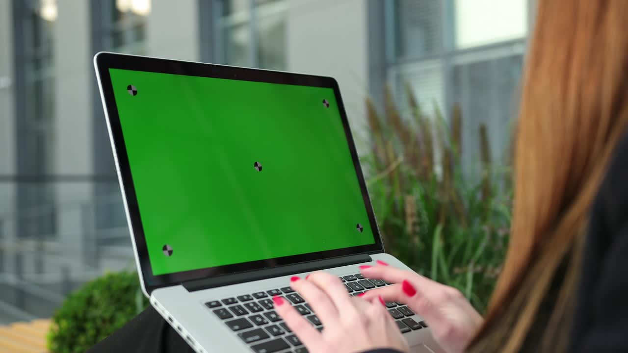 las manos de las mujeres trabajando en la computadora portátil fuera de la pantalla verde de la oficina.