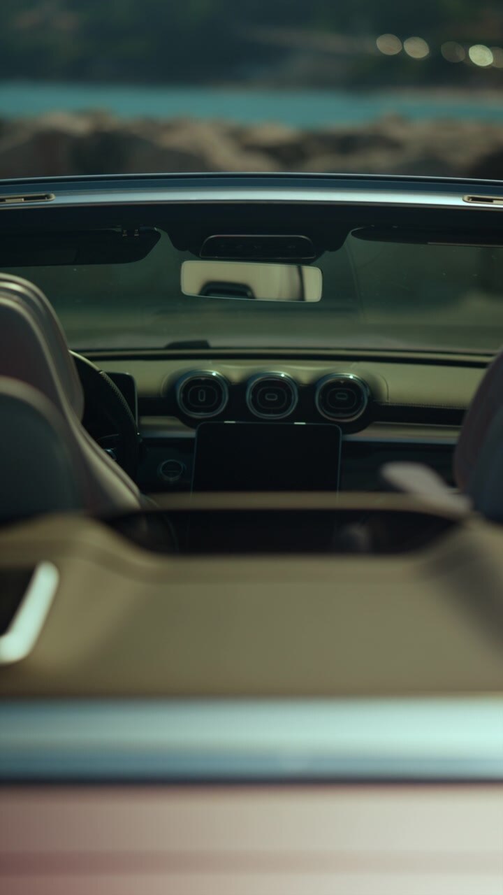 Primo piano del cruscotto interno di un'auto moderna con bocchette dell'aria e pulsanti di controllo, che evidenzia il design di un veicolo di lusso.
