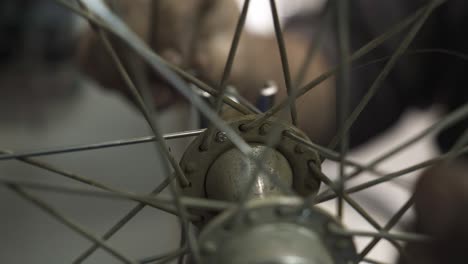 a bicycle mechanic installing a new spoke on a wheel hub