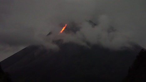 In-Einer-Nacht,-Die-Teilweise-Von-Nebel-Bedeckt-Ist,-Fließt-Glühende-Lava-Vom-Gipfel-Des-Merapi