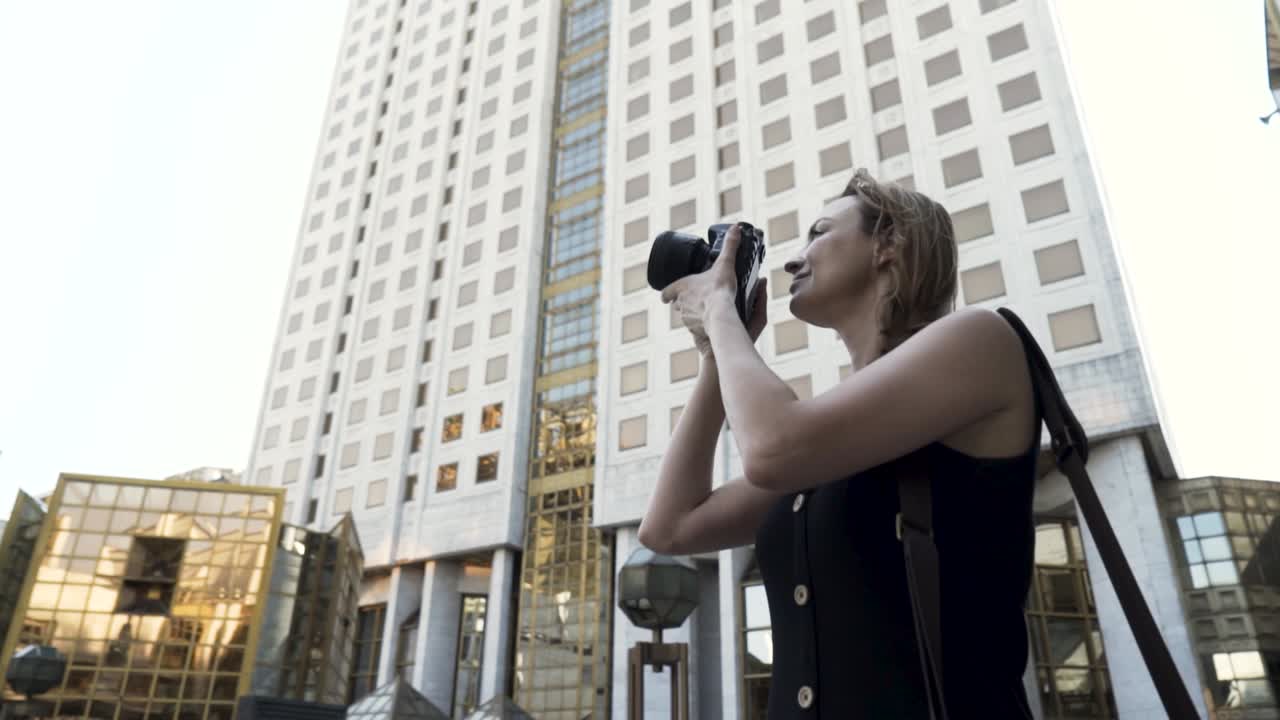 mujer tomando fotos frente a un edificio alto