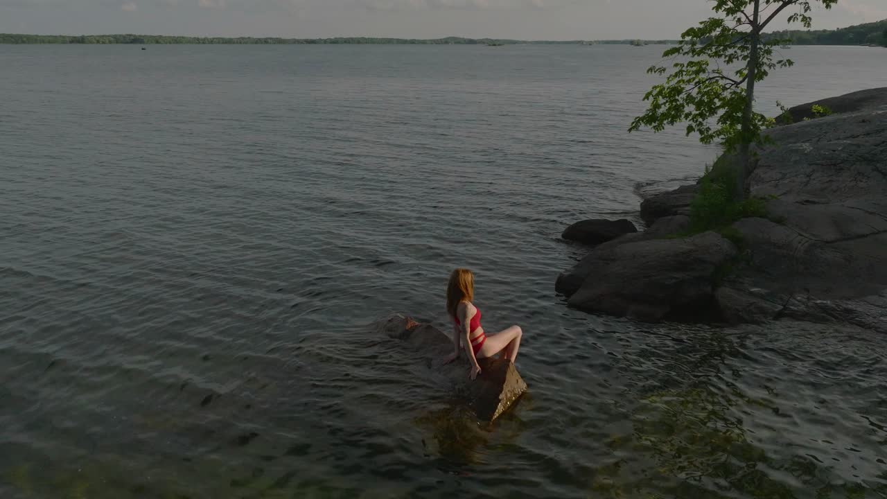 공중에 떠 있는 젊은 여성들은 바위 위에 앉아 햇빛을 받으며 여름날을 즐기고 있습니다.