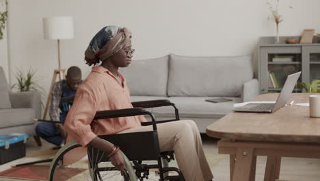 Disabled Woman Working on Computer while Carpenter Assembling Table