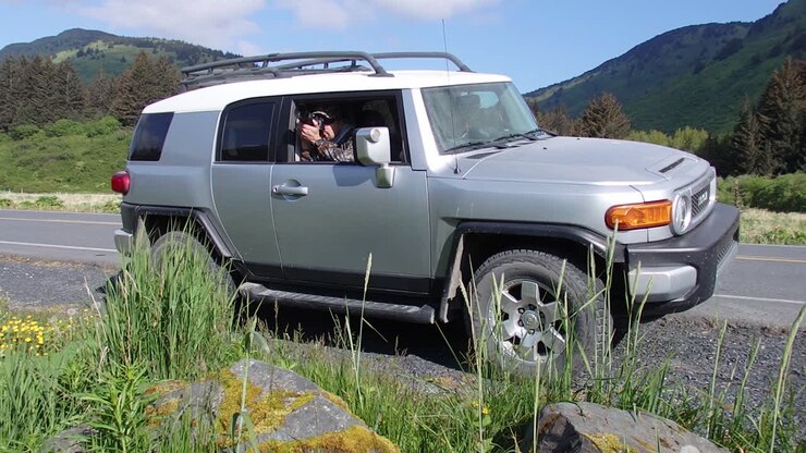 A nature and wildlife photographer capturing photos while in a Toyota fj cruiser SUV on Kodiak Island Alaska