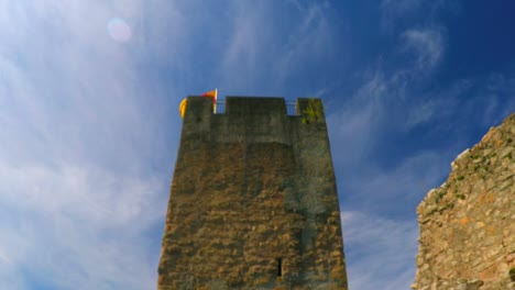 una torre de castillo del siglo xv con una orgullosa bandera ondeando en el viento