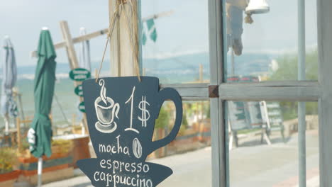 Young-man-hangs-on-the-door-of-cafe-black-board-in-city-of-Perea-Greece