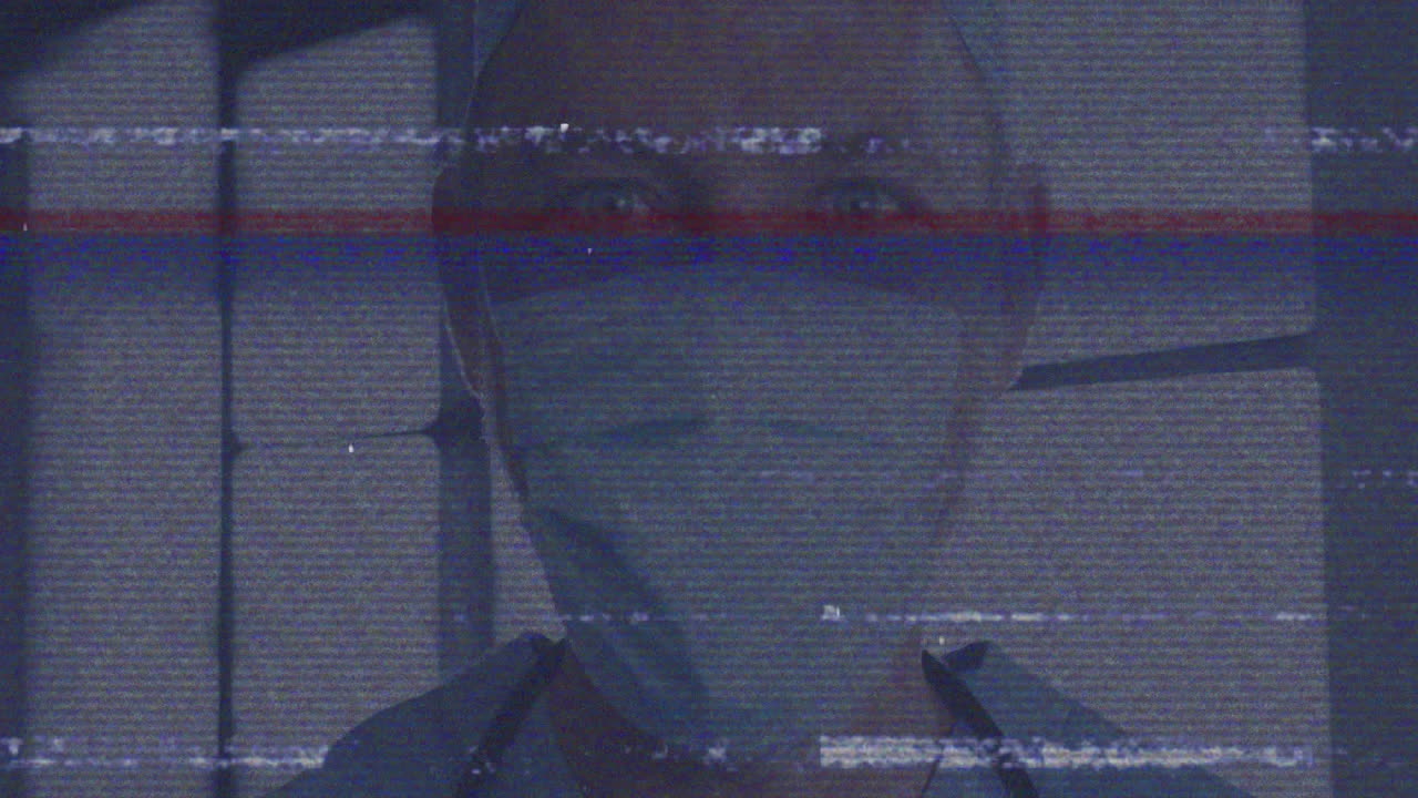 Medical professional wearing mask making eye contact in glitchy feed, showing health data overlay