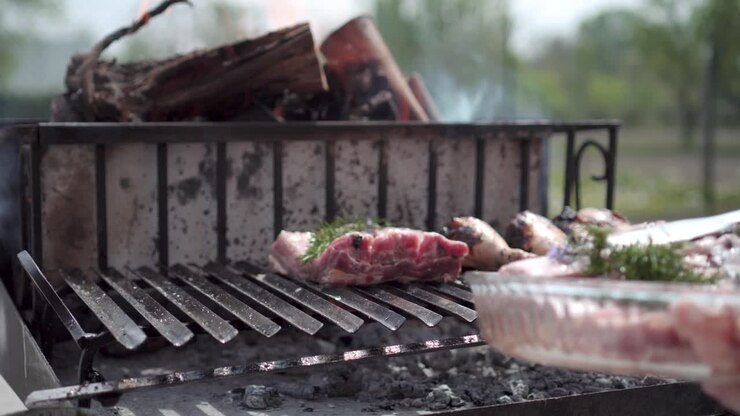 Meletakkan daging iga dengan rosemary di atas panggangan BBQ menggunakan penjepit