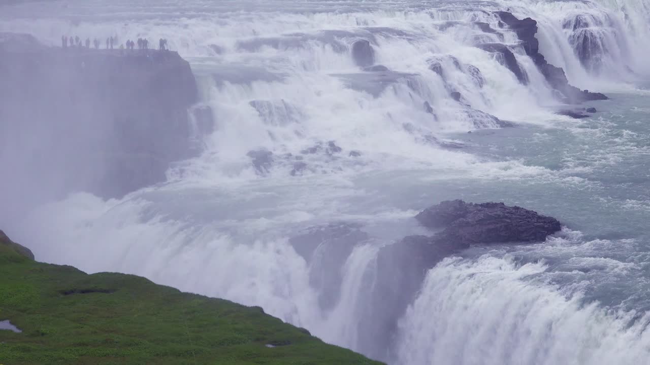 la espectacular y masiva cascada gullfoss fluye en islandia con turistas en un acantilado en la distancia