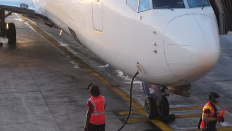 the ground crew is currently engaged in crucial maintenance work and refueling operations of an aircraft at the airport
