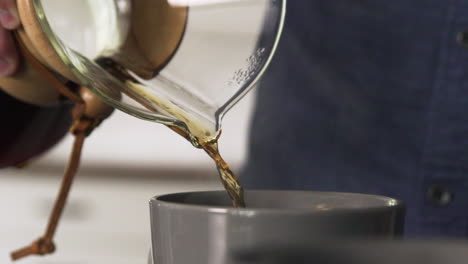 pouring coffee from a glass carafe into a cup at home, closeup slow motion