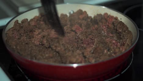 ground beef being cooked with spatula in red pan