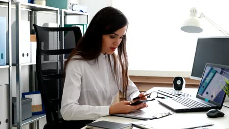 mujer de negocios hablando en teléfono inteligente y trabajando en portátil en una oficina moderna