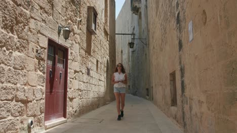 lonely female tourist walking in narrow street of mdina, malta