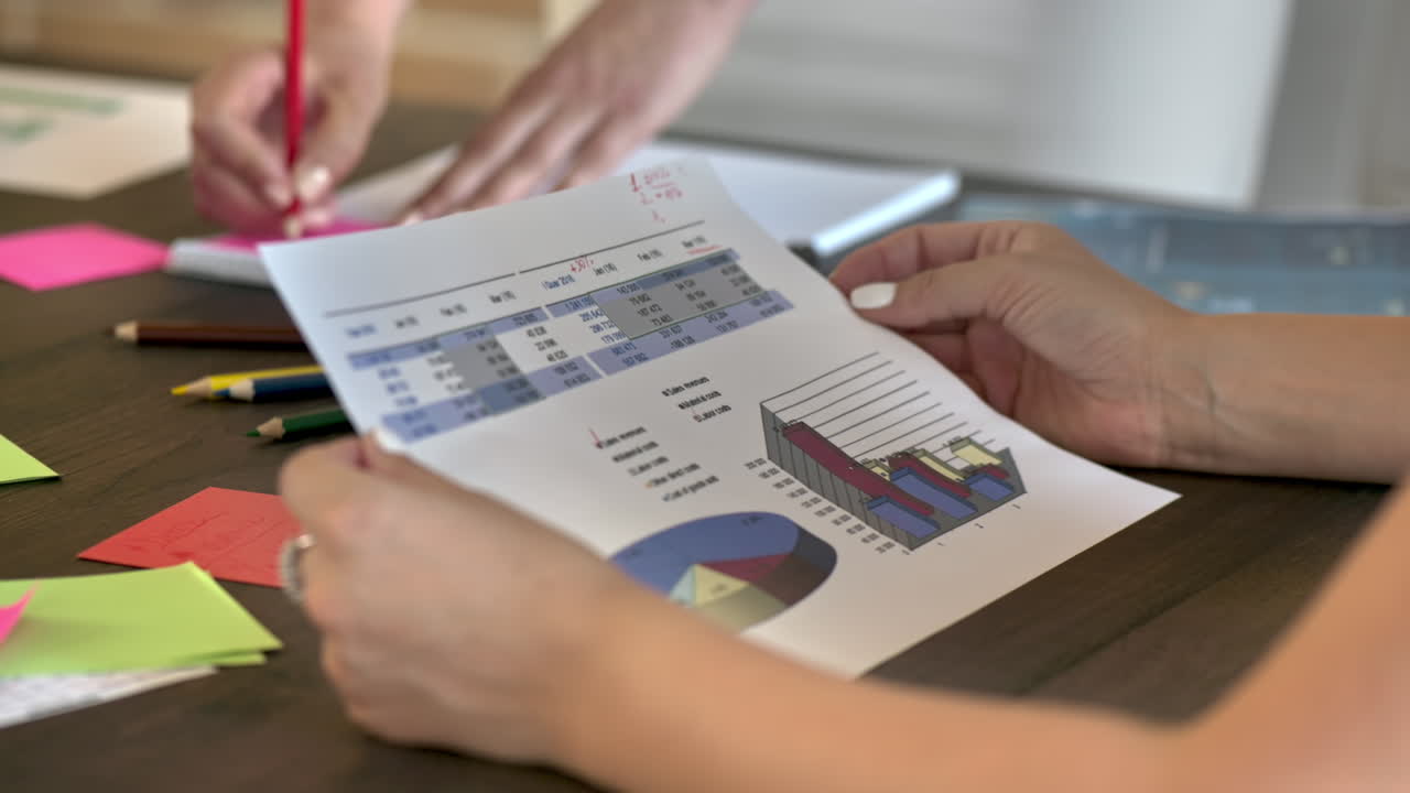 People are working and writing in the office. Papers with graphs and information