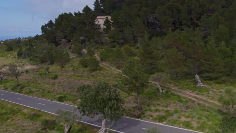 La-Moto-Está-Conduciendo-Por-La-Carretera-Rodeada-De-Naturaleza-En-La-Isla-De-Mallorca,-Aérea