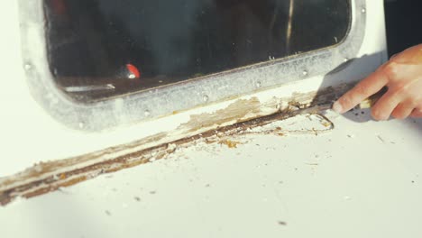 Carpenter-scraping-removing-old-sealant-on-wooden-boat-windshield