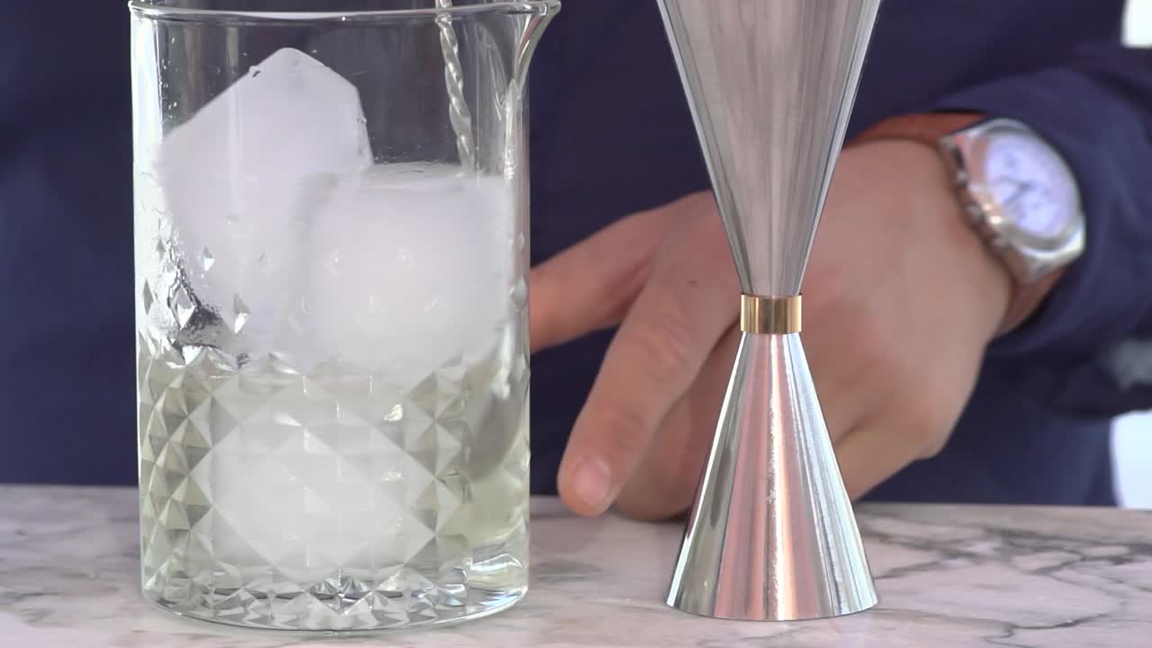 barman profesional mezclando un cóctel con hielo y alcohol fuera del bar, cámara lenta de primer plano