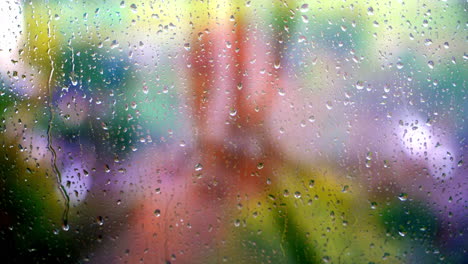 gotas de agua en un fondo de vidrio de colores iluminados. gotas de agua de lluvia corriendo hacia abajo. gota de agua cayendo sobre la superficie del vidrio.
