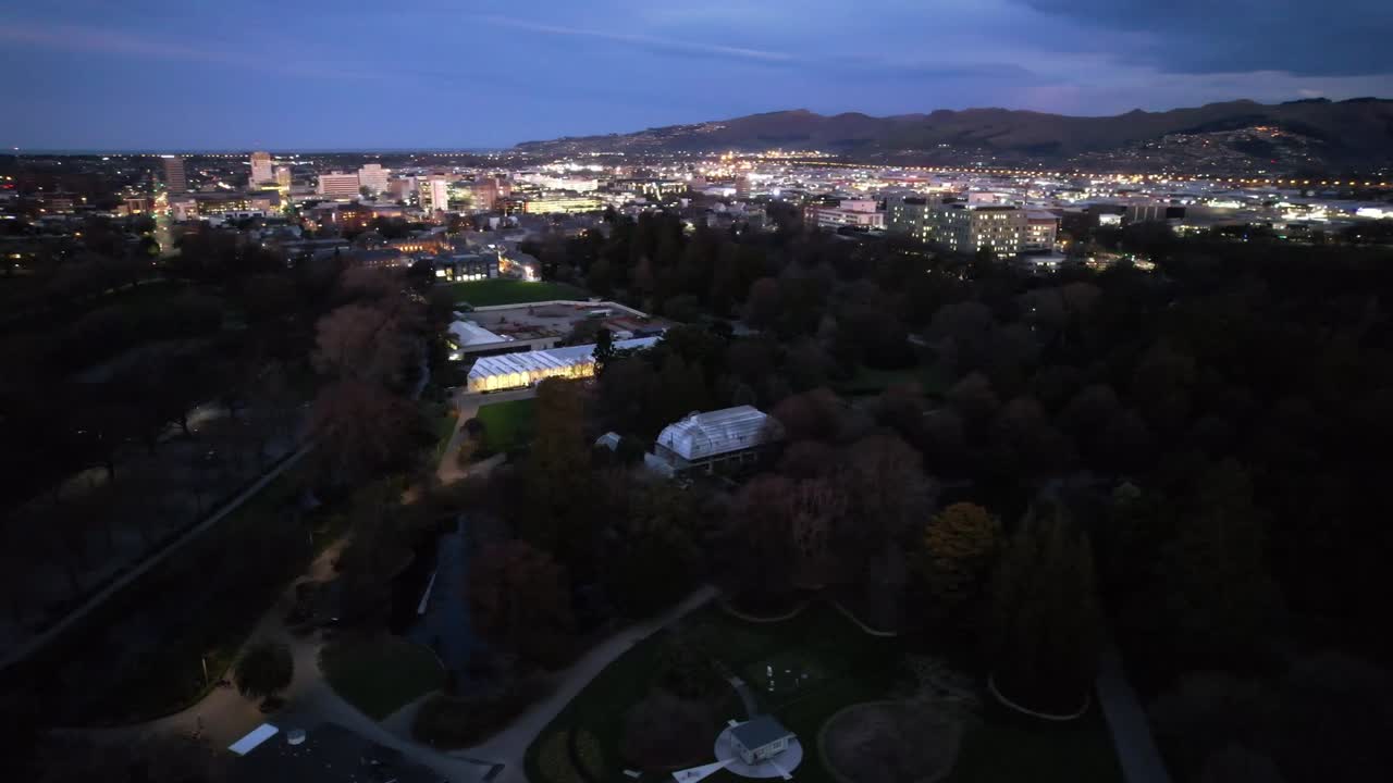 jardines de christchurch con luces de la ciudad en el fondo órbita aérea