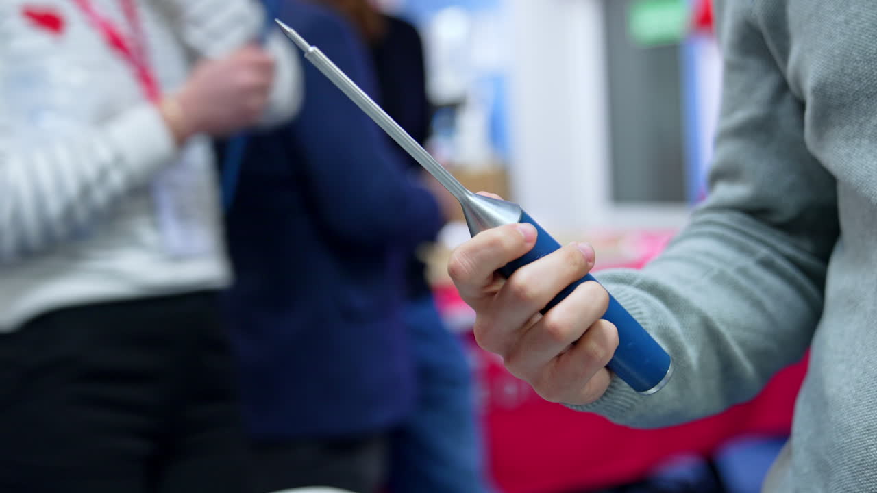 Male hand holding and turning a medical tool. Unrecognized student displaying an instrument for neurosurgery. Close up.