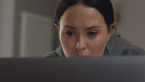 close up of anxious woman sitting indoors on sofa working from home using laptop worried about cost of living crisis 7