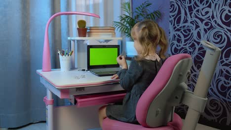 niña escolar aprende lecciones en casa usando una computadora portátil digital con pantalla verde