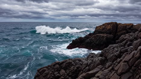 dramatic ocean waves crashing on rugged rocky coastline under stormy sky