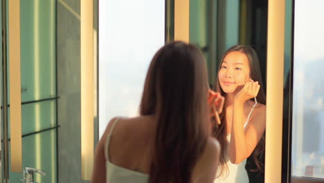 A-beautiful-woman-stands-in-front-of-a-full-length-mirror-as-she-applies-makeup-to-her-brow