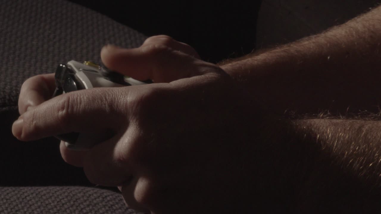 Primo piano di mani maschili bianche che giocano con un controller per videogiochi