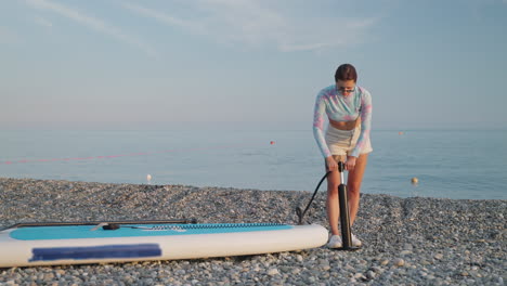 woman inflating sup on a beach