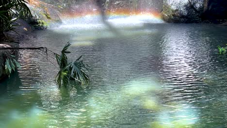 a rainbow forms over a serene waterfall