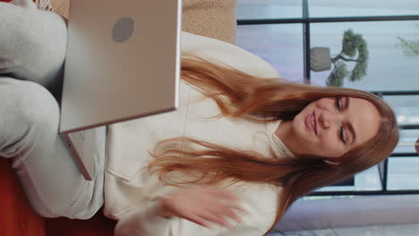 woman sitting on home couch, looking at camera, making video conference call with friends or family