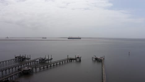 Low-rising-aerial-shot-of-cargo-ships-in-Charleston-Harbor-from-the-shores-of-Mount-Pleasant-on-a-day-with-low-visibility-in-South-Carolina