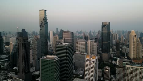 Horizonte-De-La-Ciudad-De-Bangkok-Con-Cielo-Azul-Claro,-Carro-Aéreo-A-La-Izquierda,-Vista-Aérea-De-La-Hora-Dorada-Del-Horizonte-De-Bangkok-Contra-Cielos-Azules-Claros