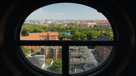 view of the city of copenhagen through the ancient round window of the screw tower 4k video