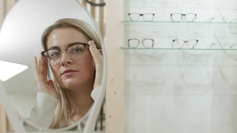 pretty woman choosing eyeglasses in optician shop
