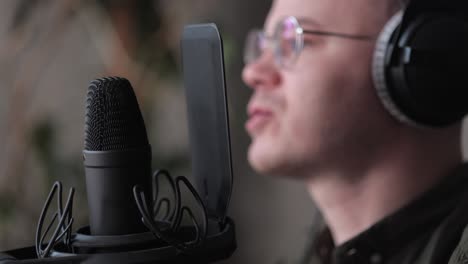 a male radio host or podcaster speaks into a microphone with headphones creates audio content in the studio or on the radio on the air