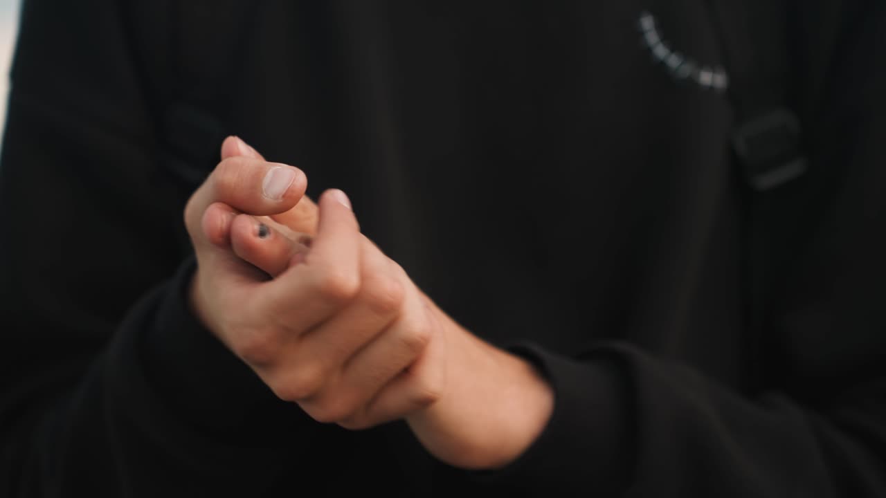 Mani al crepuscolo che massaggiano dita doloranti, persona che si prende cura di dita ferite, pressione delicata sulle nocche, manica della felpa visibile, sfondo tranquillo di bordo strada, atmosfera di cura e auto-guarigione e primo piano tattile.