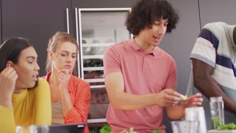un grupo feliz de amigos diversos preparando una bebida saludable en la cocina juntos