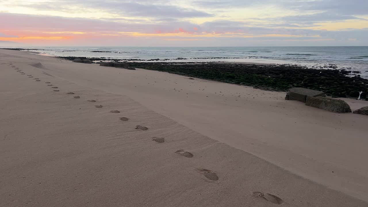 Bredt utsyn over steinete strand, mild solnedgangsatmosfære