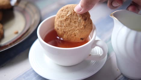 hand dipping a cookie into a cup of tea