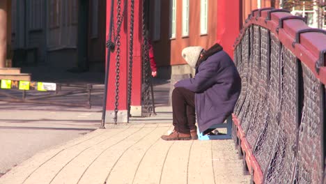 A-homeless-person-sits-on-a-bridge-in-Norway