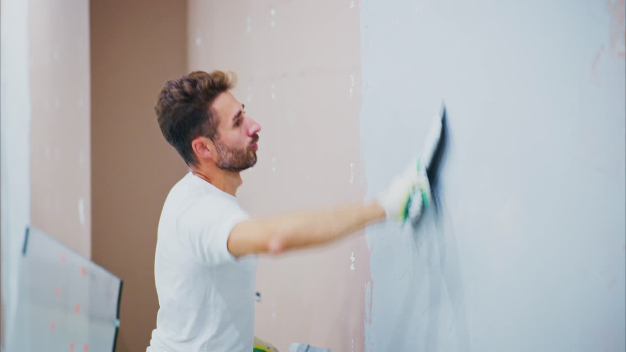 Man Applying Finishing Touches to Wall with Trowel, Demonstrating Skillful Plastering Techniques in a Modern Interior Space