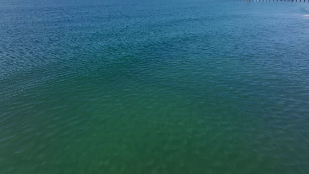 녹색 맑은 바닷물 위의 바다 쪽 부두를 드러내는 위로 기울이십시오.